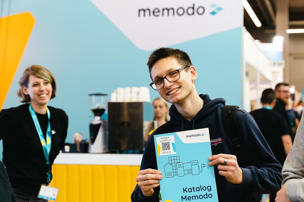 Fotografia biznesowa z targów Enex Kielce przedstawiająca uczestnika z katalogiem produktów na stoisku firmowym.